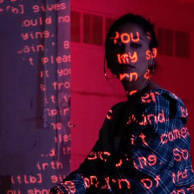 Mujer jóven sobre la cual se proyecta un código